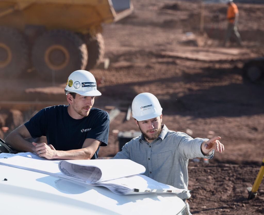 Two Benchmark employees on a job site reviewing blue prints