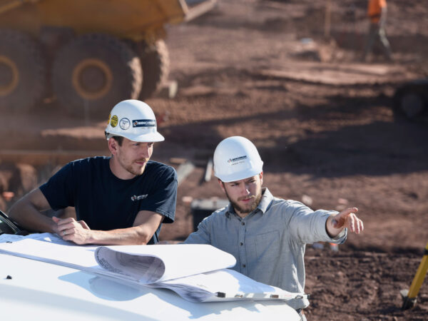 Two Benchmark employees on a job site reviewing blue prints