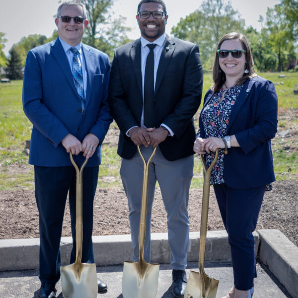 Three Benchmark team members each holding a golden shovel and smiling