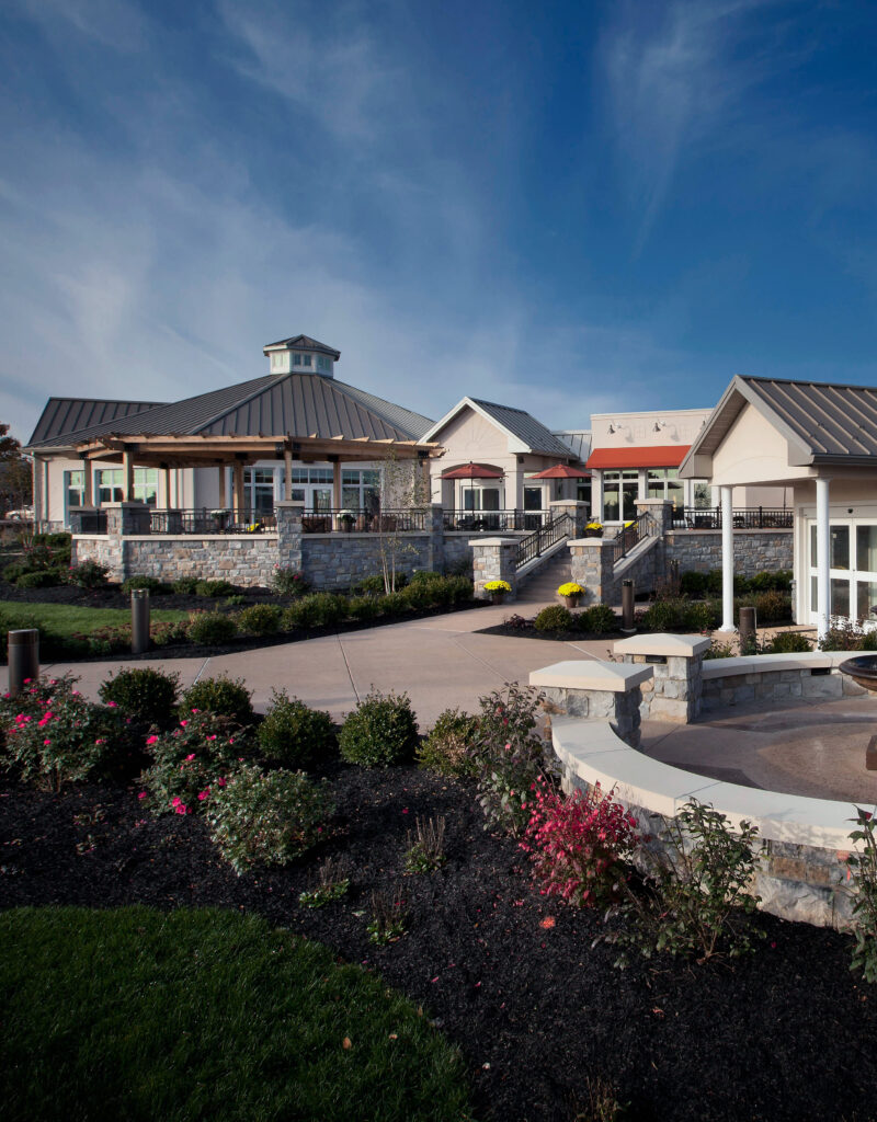 Exterior view of a landscaped facility with stone fencing and paved paths