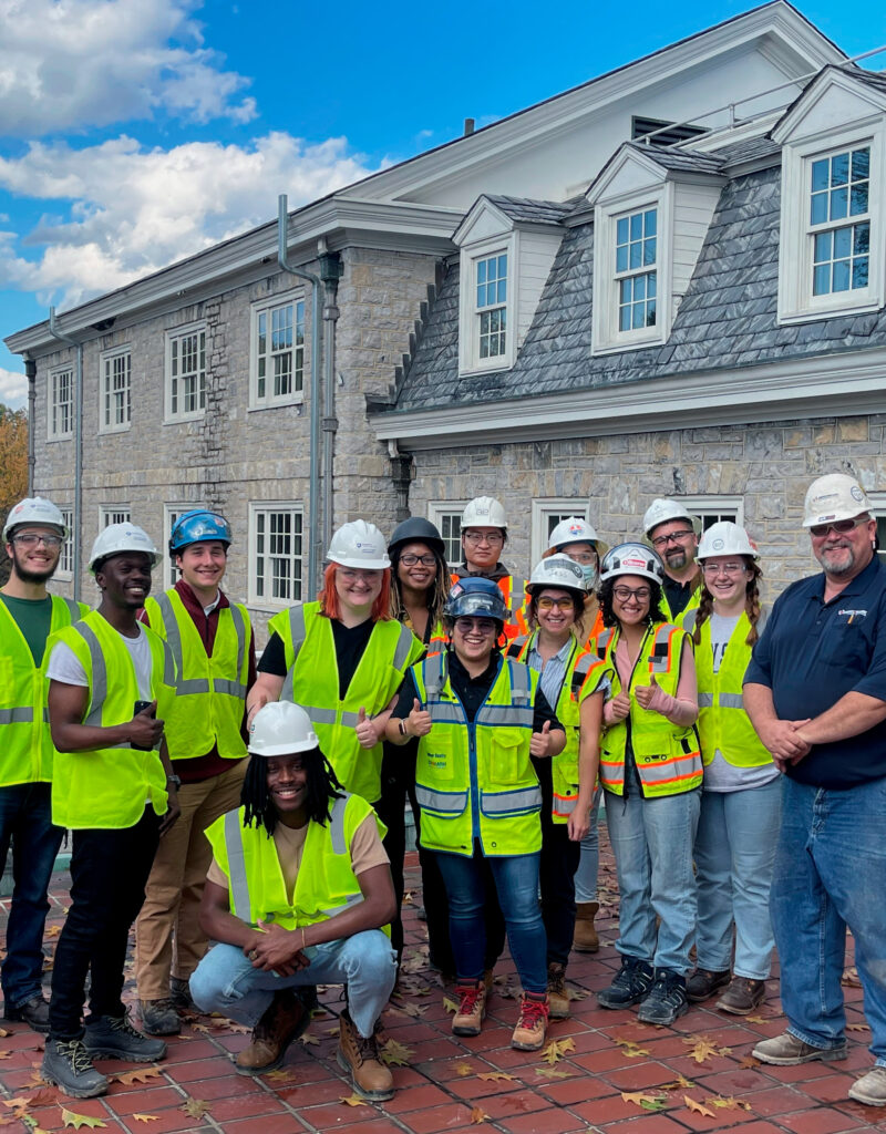 Group of Benchmark team members in safety gear smiling in front of a stone building