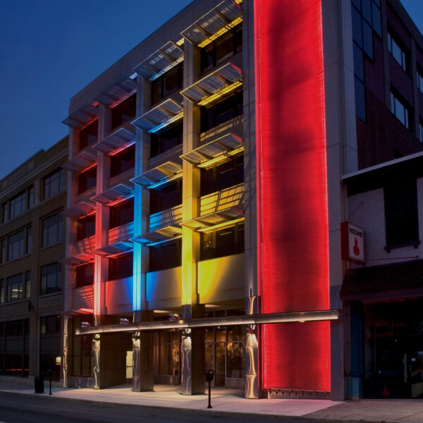 Exterior of an Education building with red, yellow, and blue lights illuminating the exterior at night