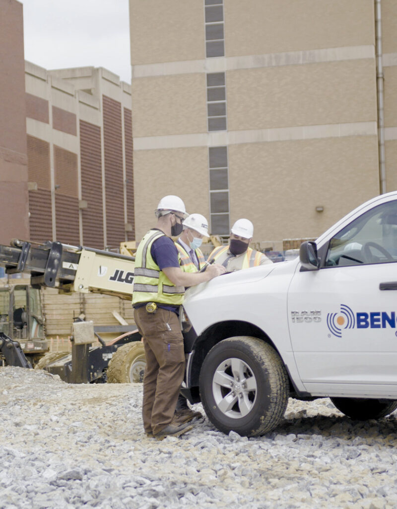 Three team members around a Benchmark pick-up truck on a job site in discussion