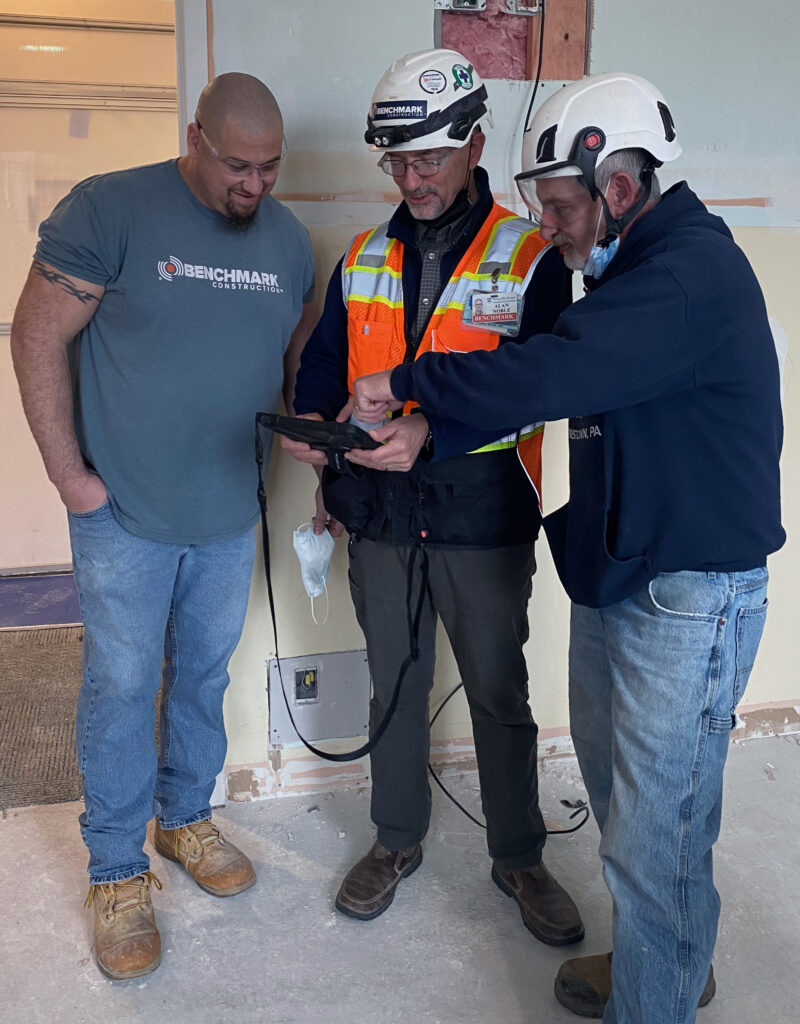 Three Benchmark team members looking at an iPad and having a discussion