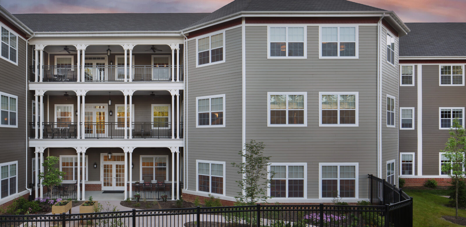 Exterior view of a multi-story residential building with decks and and outdoor fenced in yard