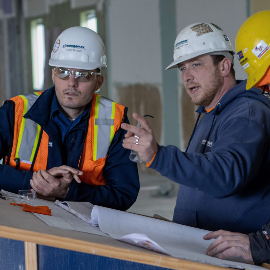 Three Benchmark employees on a job site reviewing site plans