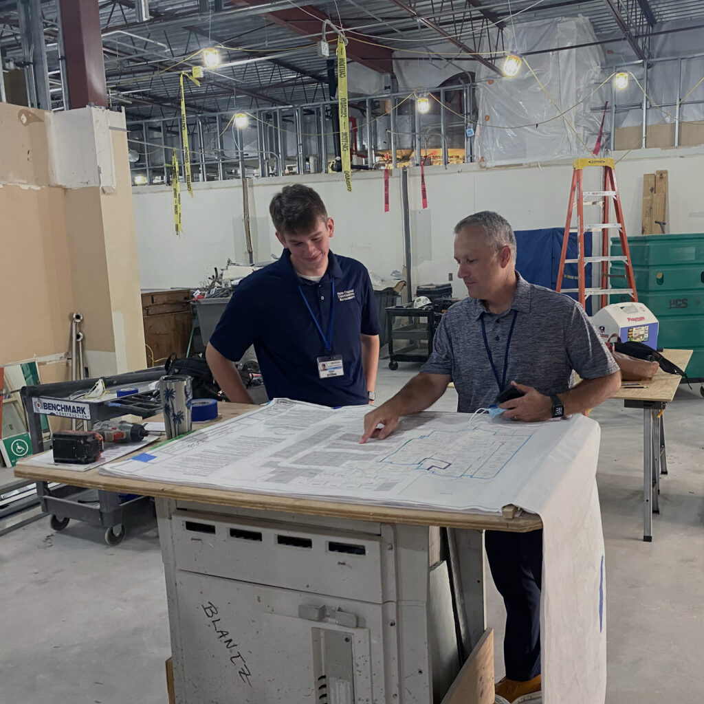 Two Benchmark employees inside a job site in progress reviewing design blueprints