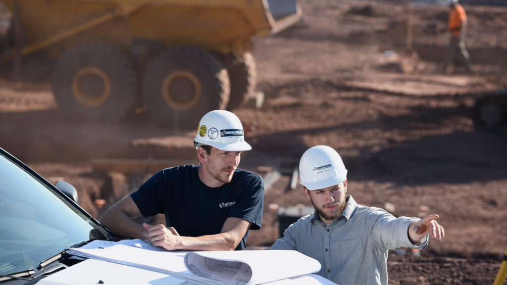 Two Benchmark team members on a job site reviewing plans